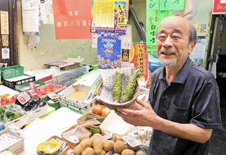 自慢のワサビを手にする藤原明さん。「この店の２階で生まれて小中高とここから通った。子どもの頃から店を手伝いよったよ」＝神戸市灘区水道筋３