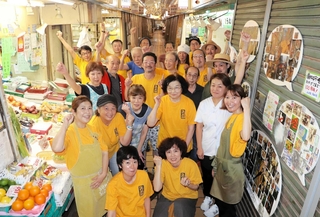 １９２５年８月の開設から歴史を重ね、１０１年目に入る市場。「みんな、集合や！」のかけ声で、そろいのシャツを着た店主たちが出てきた＝灘区水道筋３