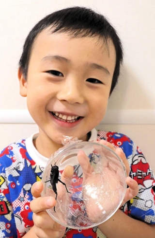 捕まえたバッタを手に笑顔を見せる村上功ちゃん＝神戸市東灘区