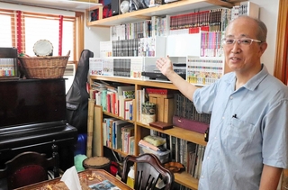 漫画の本棚の横にピアノ。いこいの広場３丁目のアットホームな室内を案内する矢野健太郎さん＝神戸市兵庫区湊川町３