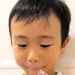 捕まえたバッタを見つめる村上功ちゃん＝神戸市東灘区