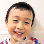 捕まえたバッタを手に笑顔を見せる村上功ちゃん＝神戸市東灘区