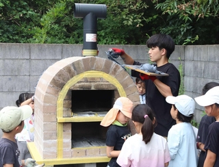 ピザ窯作りの仕上げ作業に取り組む学生と子どもたち＝ふれあいの里おくっちょ