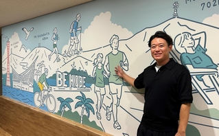 神戸の風景とアウトドアを楽しむ人たちを描いた壁と長尾洸太朗社長＝神戸市中央区脇浜海岸通１
