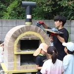 ピザ窯作りの仕上げ作業に取り組む学生と子どもたち＝ふれあいの里おくっちょ