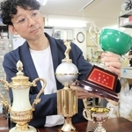 寄付予定のトロフィーを手に「どんな形のものでも大歓迎」と呼びかける藤井淳史社長＝毛利マーク