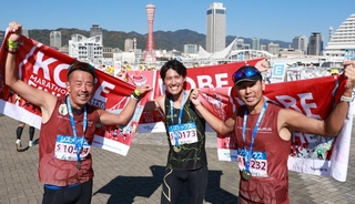 同郷の仲間とともに完走し、タオルを掲げる樋口正明さん（中央）＝神戸市中央区東川崎町１（撮影・鈴木雅之）