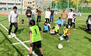 コーチの江口倫司さん（左端）から、サッカーのプレーの基本を教わる親子＝神戸リガッタ・アンド・アスレチック倶楽部