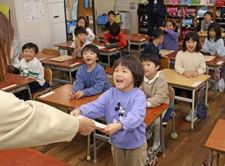 担任の先生から一人ずつ通知表を受け取る子どもたち＝長田南小学校