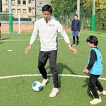 コーチの江口倫司さん（中央）から、サッカーのプレーの基本を教わる親子＝神戸リガッタ・アンド・アスレチック倶楽部