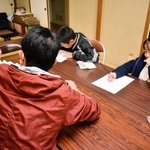 男の子に寄り添って勉強を教える。「最初の頃は会話も敬語でした」と笑う＝長田区東尻池町４