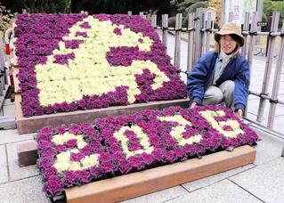 ２色の葉ボタンで馬を描いた干支飾りと制作した野下彩香さん＝神戸市須磨区東須磨、市立須磨離宮公園