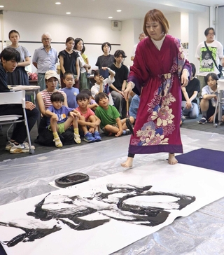 阪神・淡路大震災について考える催しで、思いをしたためる和田彩さん。「生」のほかに「舞」などの文字を大書した＝２０２５年８月、神戸大学