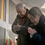 母の名が刻まれた銘板に手を合わせる三木健次さん（左）と妻の貞子さん＝１７日午前７時１分、東遊園地（撮影・大田将之）