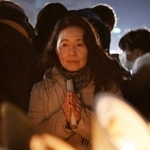 祖母を亡くした白石美貴子さん。竹灯籠を見つめ手を合わせる＝１７日午前５時４０分、東遊園地（撮影・大田将之）