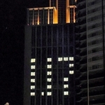 竹灯籠に手を合わせる人たちを、ビルの「１．１７」が見守る＝１月１７日午前５時１０分、東遊園地