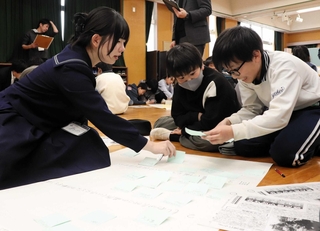 高校生の助言を受けながら、自分の考えをまとめた付箋を貼る小学生＝横尾小学校