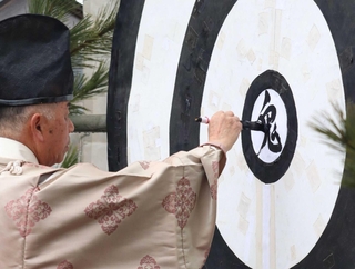 的の中心に「鬼」の文字を書く宮司＝神戸市北区淡河町勝雄、淡河八幡神社
