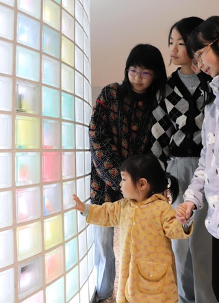 カラフルなシートを貼り終えた柱を外から眺める参加者＝中央区三宮町１