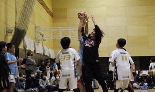 必死に手を伸ばしてボールを取り合う小学生と大学生＝神戸市立磯上体育館（提供）