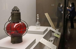 船の進路を示す「金赤色ガラス舷灯」（左）など名品が並ぶ特別展＝神戸市立博物館