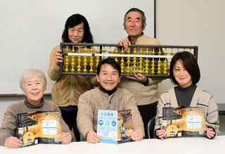授業で使うそろばんとともに、長田の名所を紹介する冊子「まちあるき」を紹介する生徒＝長田商業高校