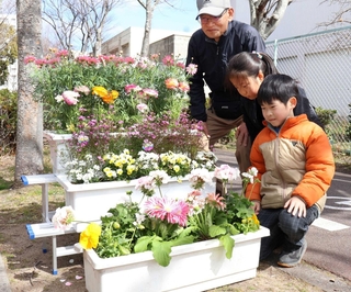 竜が台小学校前に花を飾る合田晴雄委員長と児童＝須磨区竜が台６
