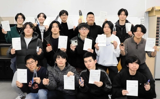 お気に入りの工具と合格通知書を持って笑顔を見せる電気コースの３年生１４人＝神戸工科高校