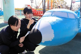 飛行塔の遊具に色を塗る神戸海星女子学院の生徒＝王子動物園
