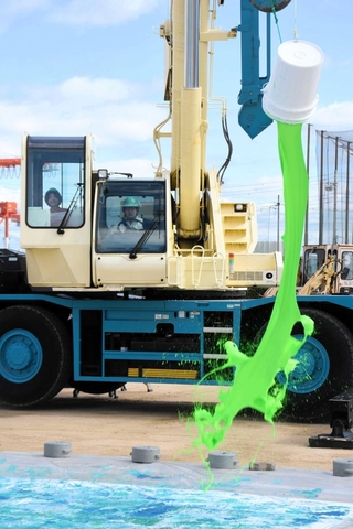 移動式クレーンを使い、操縦役と指示役が協力してペンキをまいていく＝港湾職業能力開発短期大学校神戸校