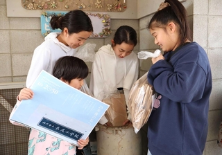 未来の自分に宛てた手紙や写真などをタイムカプセルに入れる児童＝長尾小学校