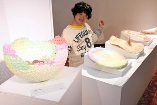 パルプを使った作品の前で笑顔を見せる山本祥太郎さん＝こころのアートギャラリー