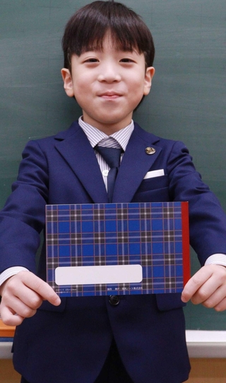 神戸タータンの自由帳を手にする新１年生＝こうべ小学校