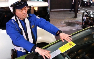 「放置車両確認標章」を貼り付ける警察官＝神戸市中央区中山手通１