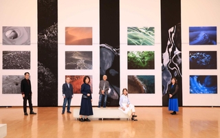 新たな表現に挑戦している出展者。背景はメンバーの一人、野口克美さんの作品＝県立美術館