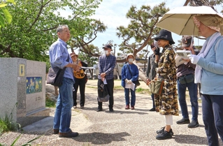 「火垂るの墓」の石碑の前で、清太と節子が空襲から逃げた道筋を解説する辻川敦さん（左端）＝神戸市灘区記田町１、石屋川公園
