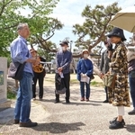 「火垂るの墓」の石碑の前で、清太と節子が空襲から逃げた道筋を解説する辻川敦さん（左端）＝神戸市灘区記田町１、石屋川公園