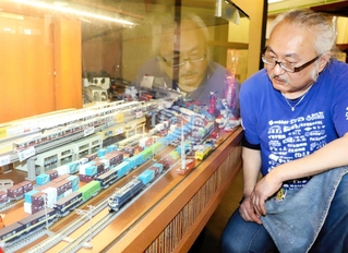 鉄道ジオラマを見つめる萩尾太一さん。気が付けば、ショーケースがいっぱいになるまで広がった＝ハートフルみなとがわ