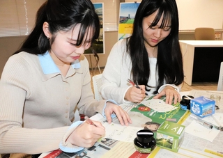 完成したインクで文字を書く学生＝神戸市中央区港島１、神戸学院大学