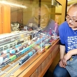 鉄道ジオラマを見つめる萩尾太一さん。気が付けば、ショーケースがいっぱいになるまで広がった＝ハートフルみなとがわ