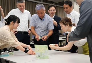 学生の考えたパッケージを手に取り、質問する担当者ら＝神戸芸術工科大学