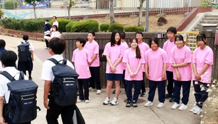 ピンクのＴシャツを着てあいさつする生徒会の生徒ら＝小部中学校