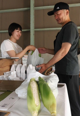 予約客に「ねおきの白コーン」を手渡す小林衣美さん（左）＝西区押部谷町西盛