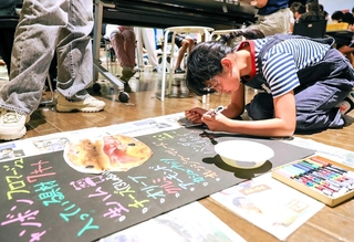 ２０２４年のワークショップで、商品看板を描く参加者（デザイン・クリエイティブセンター神戸提供）