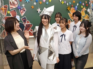 大阪・関西万博で実際に使われた衣装を試着する生徒ら＝神戸女子洋裁専門学校