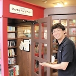 電話ボックス風のミニ図書館を紹介する岡部亮司さん＝喫茶アップルハウス