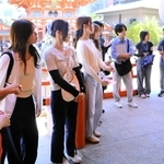 永山広大さん（右端）から英語で生田神社の説明を受ける大学生ら＝神戸市中央区下山手通１