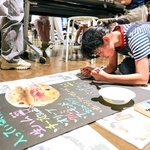 ２０２４年のワークショップで、商品看板を描く参加者（デザイン・クリエイティブセンター神戸提供）