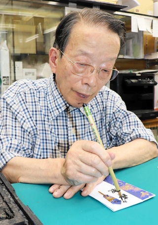 祝い袋に名前をしたためる佐藤実さん＝神戸市兵庫区東山町１、佐藤紙店