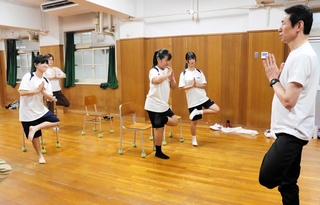 片脚を上げるヨガのポーズに挑戦する中学生ら＝原田中学校